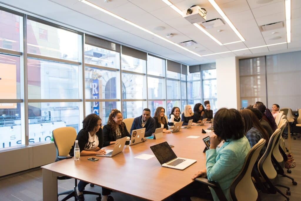 group of people sitting beside rectangular wooden table with laptops, professionals in international higher education